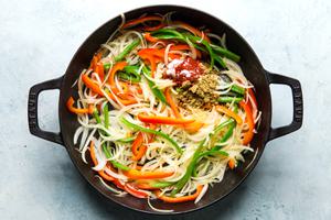 thinly sliced onions, green and red bell peppers cooked in a skillet with spices