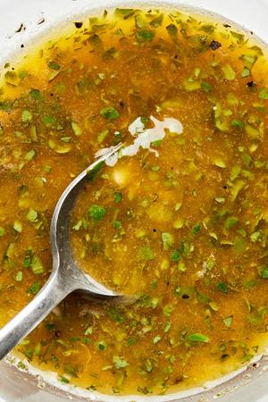 olive oil, vinegar, oregano, lemon zest, lemon juice, garlic, pepper, and salt being stirred together in a bowl