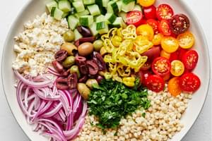 couscous, feta, olives, cucumber, tomatoes, pepperoncini, onion, and parsley in a large bowl