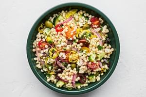 mediterranean couscous salad made with feta, Greek olives, cucumber, tomato, pepperoncini, red onion and parsley