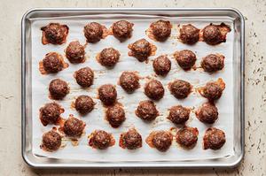 Mediterranean meatballs made with ground beef, onion, spices, parsley, eggs & bread crumbs on a parchment lined baking sheet