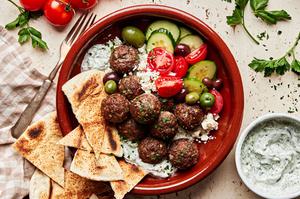 mediterranean meatballs with tzatziki served over rice pita bread, tomatoes, cucumbers and olives