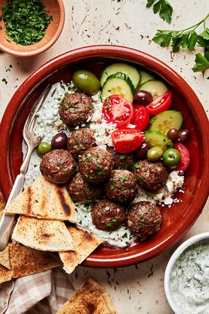 mediterranean meatballs with tzatziki served over rice pita bread, tomatoes, cucumbers and olives
