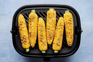 corn on the cob being cooked on the grill