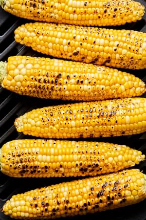corn on the cob being cooked on the grill
