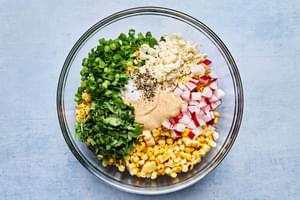 grilled corn, radishes, green onions, cilantro, Cotija cheese, lime juice, salt, pepper & chipotle mayonnaise in a bowl