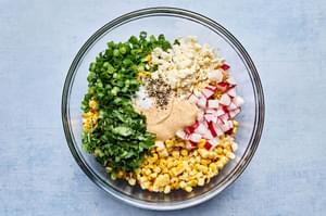 grilled corn, radishes, green onions, cilantro, Cotija cheese, lime juice, salt, pepper & chipotle mayonnaise in a bowl