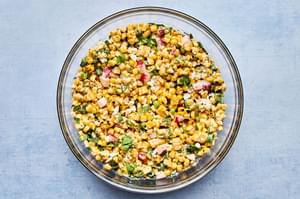 a bowl of Mexican Street Corn Salad with Chipotle Crema made with radishes, green onions, cilantro, cotija and lime juice