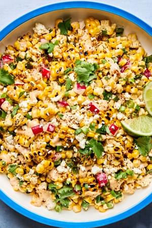 a bowl of Mexican Street Corn Salad with Chipotle Crema made with radishes, green onions, cilantro, cotija and lime juice