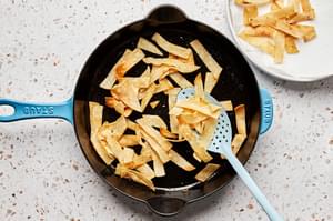 corn tortillas cut in strips being fried in vegetable oil