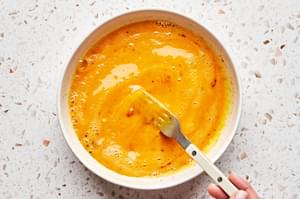 eggs being whipped in a bowl with chili powder and salt