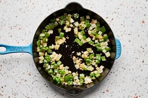 bell pepper, onion and garlic being cooked in a skillet