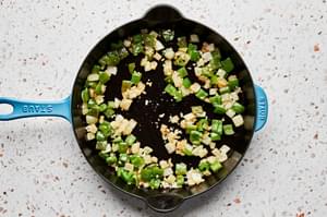 bell pepper, onion and garlic being cooked in a skillet