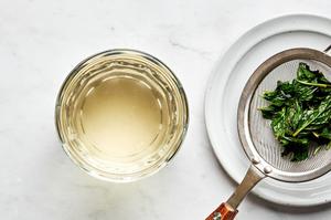 mint leaves being strained out of homemade mint simple syrup