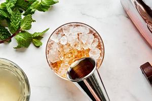 bourbon being poured into a glass with crushed ice