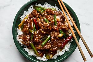 a bowl of homemade mongolian beef served on top of white rice with chop sticks