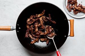 thinly sliced steak tossed with Shaoxing wine, soy sauce and cornstarch being cooked in a wok