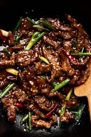 a pan of mongolian beef made with shaoxing wine, soy sauce, brown sugar, ginger, garlic, green onion and chili peppers