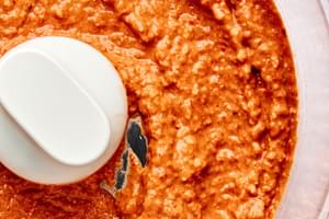 Muhammara in a food processor made with roasted red peppers, walnuts, lemon juice, pomegranate molasses, spices & olive oil