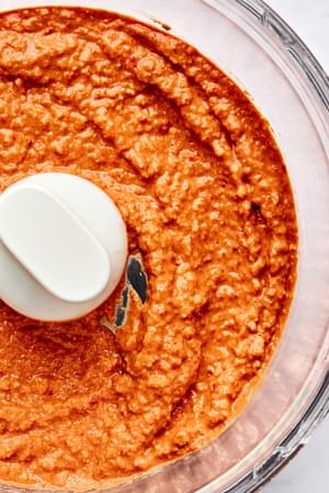 Muhammara in a food processor made with roasted red peppers, walnuts, lemon juice, pomegranate molasses, spices & olive oil