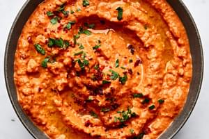 Bowl of Muhammara made with roasted red peppers, walnuts, breadcrumbs, lemon juice, pomegranate molasses, spices & olive oil