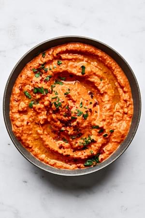 Bowl of Muhammara made with roasted red peppers, walnuts, breadcrumbs, lemon juice, pomegranate molasses, spices & olive oil