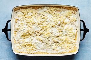 homemade béchamel sauce, cooked lasagna noodles, ricotta, mozzarella and cooked mushrooms being layered in a casserole dish