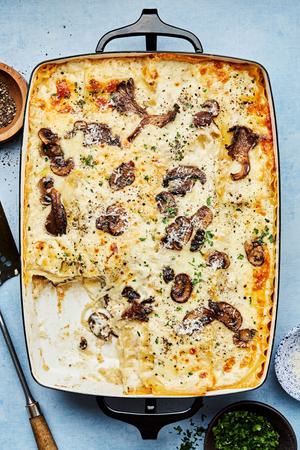 homemade mushroom lasagna fresh from the oven topped with pepper, Parmesan and parsley with a slice taken out
