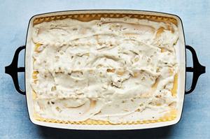 homemade béchamel sauce, cooked lasagna noodles, ricotta, mozzarella and cooked mushrooms being layered in a casserole dish