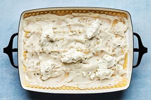 homemade white sauce, cooked lasagna noodles, ricotta, mozzarella and cooked mushrooms being layered in a casserole dish