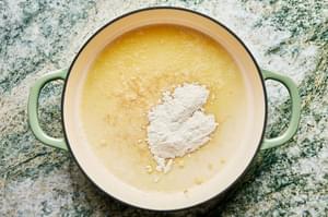 butter and flour being cooked in a braiser to form a thick paste