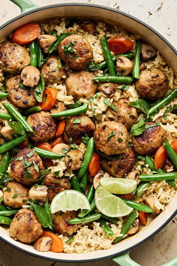 One Pot Chicken Meatball and Green Curry Rice in skillet with green beans and carrots topped with fresh basil and lime juice