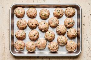raw meatballs on a baking sheet made with chicken, basil, garlic, green onions, fish sauce, curry, sugar, cornstarch & salt