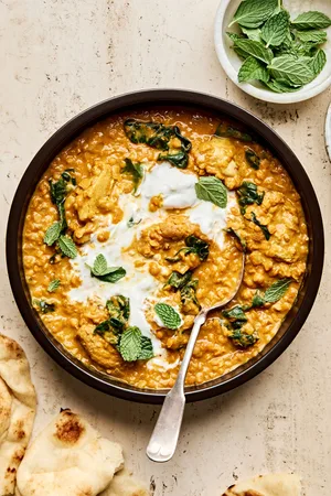 a bowl of one pot chicken and lentils featuring tender chicken simmered with lentils & aromatic herbs topped with fresh mint