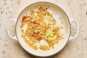 chopped onion, garlic and ginger being cooked in olive oil in a braiser