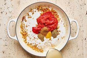 tomato paste, spices, stock, tomatoes & coconut milk added to a braiser with onion, garlic & ginger