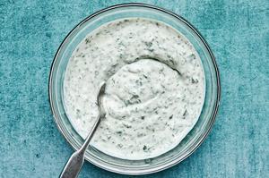 herb yogurt made with greek yogurt, cilantro, dill, clove, lemon juice and salt in a glass bowl with a spoon