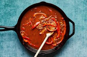 chicken stock, bell peppers, shallots, rice and spices being cooked in a skillet