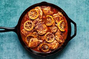chicken stock, bell peppers, shallots, rice, spices, chicken and lemon slices being cooked in a skillet