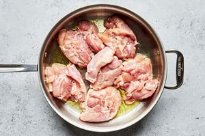skinless chicken thighs seasoned with salt being browned in olive oil in a large pan