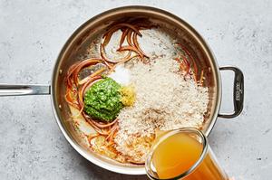 sliced red onion, chicken stock, rice, pesto, lemon zest, lemon juice and salt cooking in a large skillet