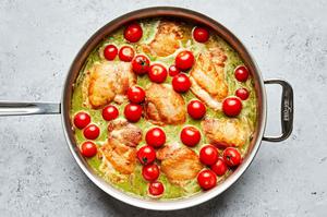 chicken thighs, cherry tomatoes, red onion, chicken stock, rice, pesto, lemon zest, lemon juice and salt cooking in a skillet