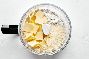 flour, baking powder, baking soda, salt, minced onion and butter being pulsed in a food processor