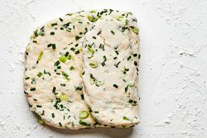 onion chive biscuit dough rolled out and folded on the counter