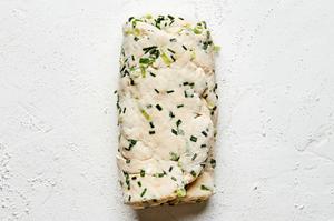 onion chive biscuit dough rolled out and folded into thirds on the counter