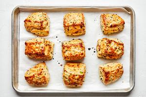 9 homemade onion chive biscuits on a parchment lined baking sheet