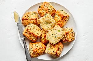 homemade onion chive biscuits being buttered on a plate