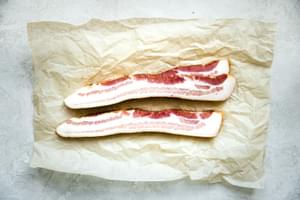 Thick sliced raw bacon on parchment paper