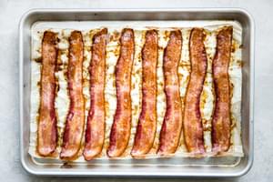 8 slices of baked bacon on a parchment lined baking sheet fresh out of the oven and perfectly crispy