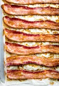 Oven-baked bacon on a parchment lined baking sheet, fresh from the oven and perfectly crispy.